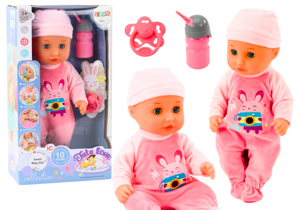 Babypuppe im rosa Pyjama pinkelt Flaschenschnullergeräusche